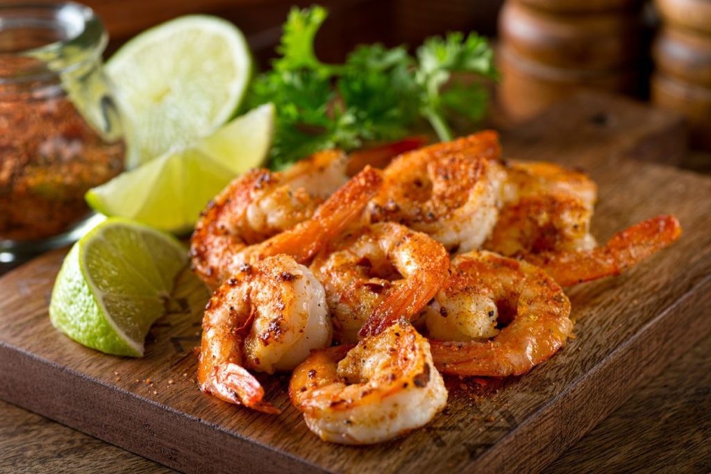 a wooden board with roasted shrimps on top