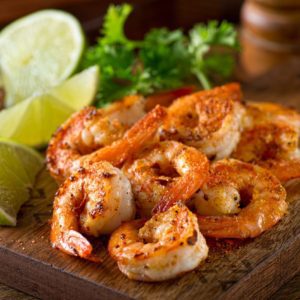 a wooden board with roasted shrimps on top