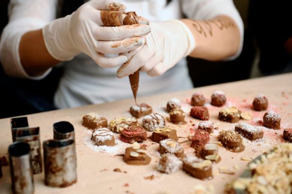 A pastry baker putting icing on chocolate truffles