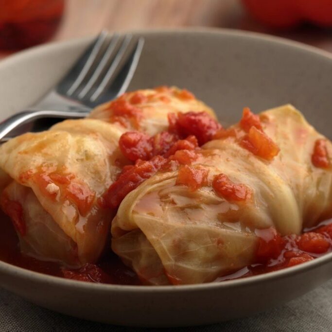 Two cabbage rolls with tomato sauce in a bowl