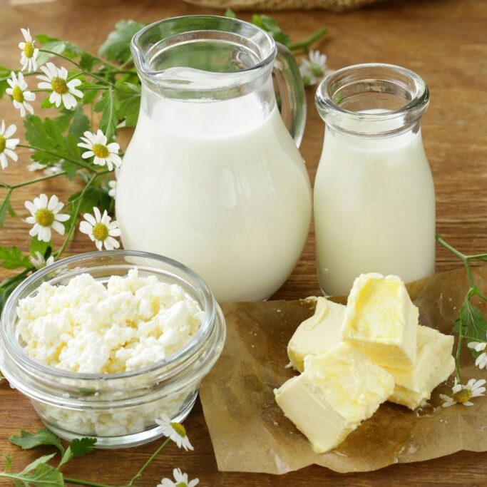 Two jugs of fresh milk and butter in a bowl