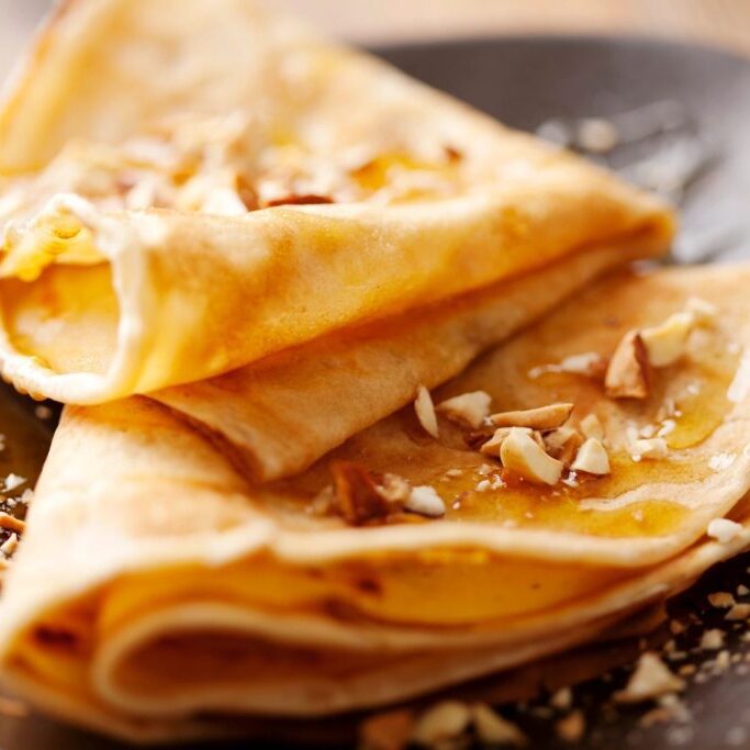 A pair of cooked crepes and walnuts on them